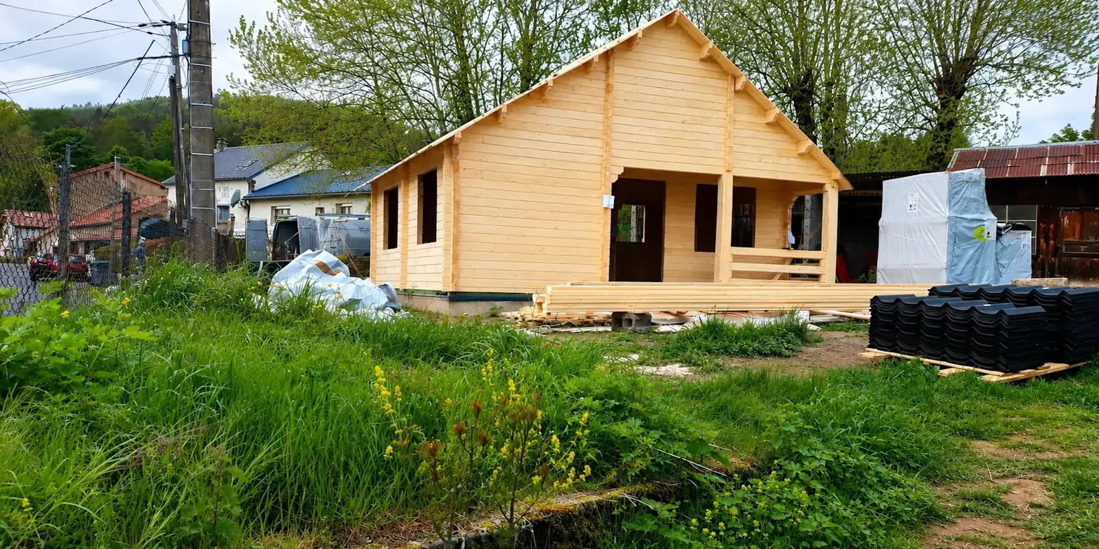 Chalet bois en kit STMB Construction en cours de montage après la livraison des matériaux sur le terrain du client.