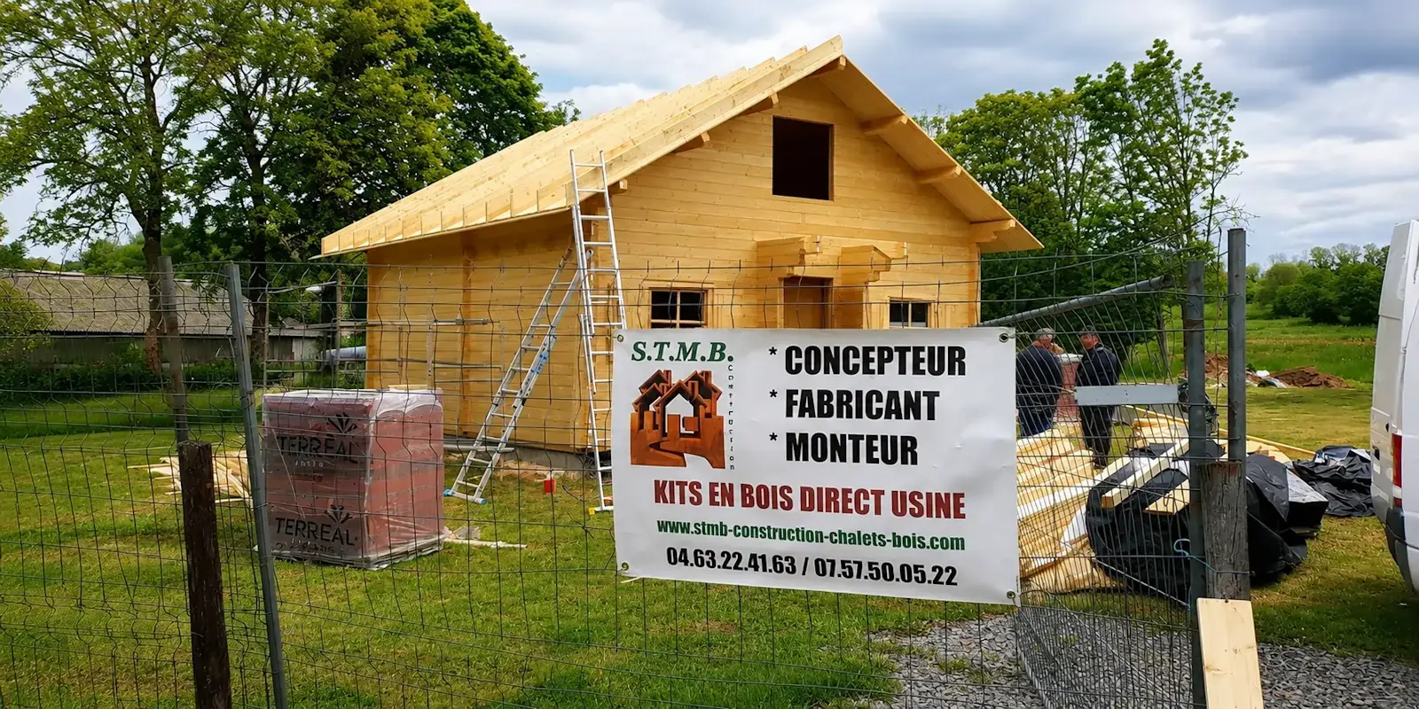 Chantier de montage d'un chalet en bois en kit STMB Construction après la livraison des éléments sur le terrain du client.