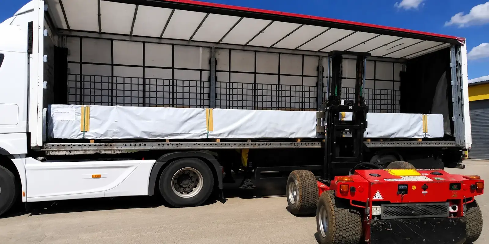 Livraison à domicile d'un kit chalet bois avec déchargement sécurisé par camion de transport spécialisé.