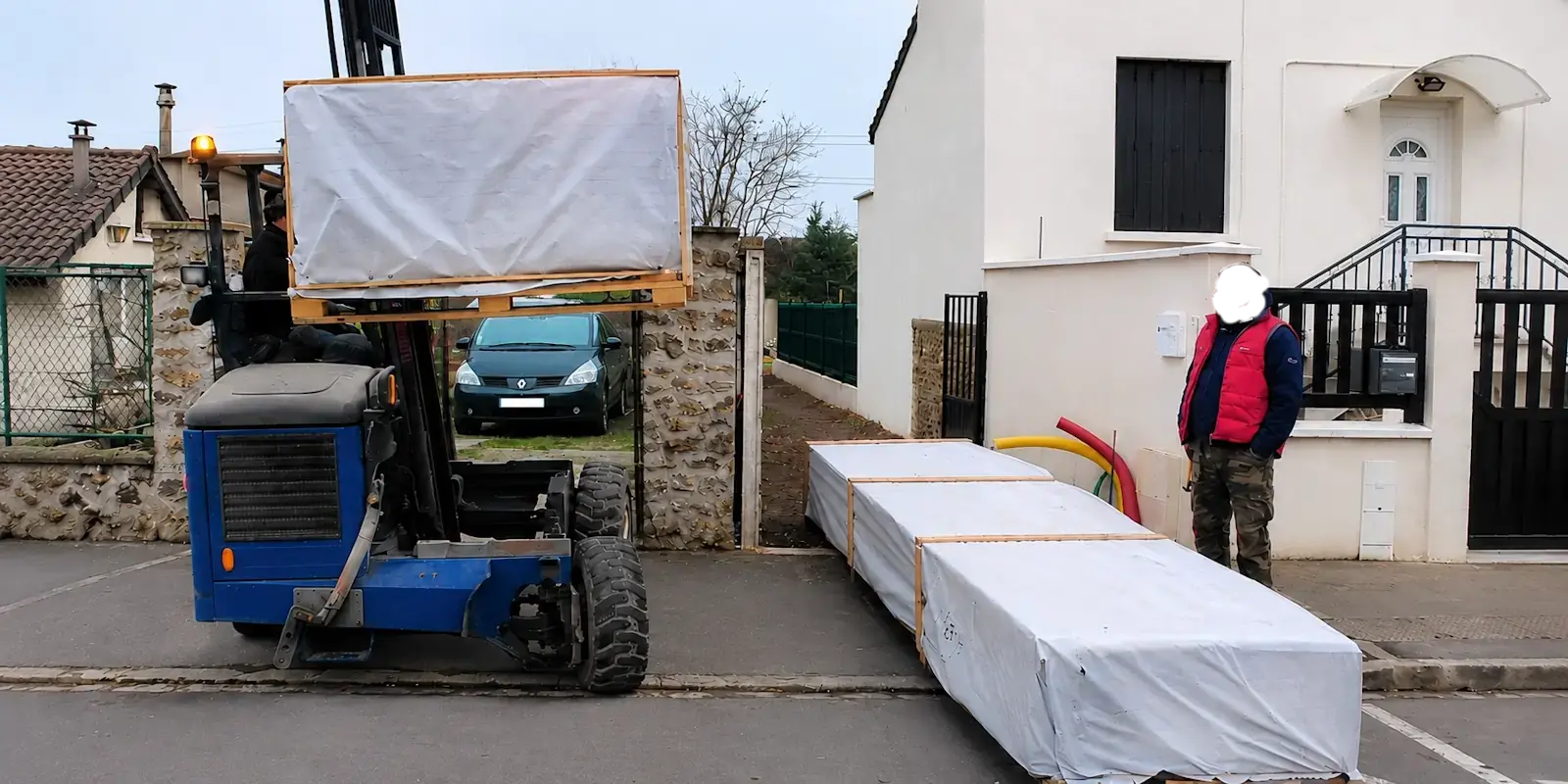 Livraison à domicile d'un kit chalet bois avec déchargement sécurisé au chariot élévateur devant le terrain du client.