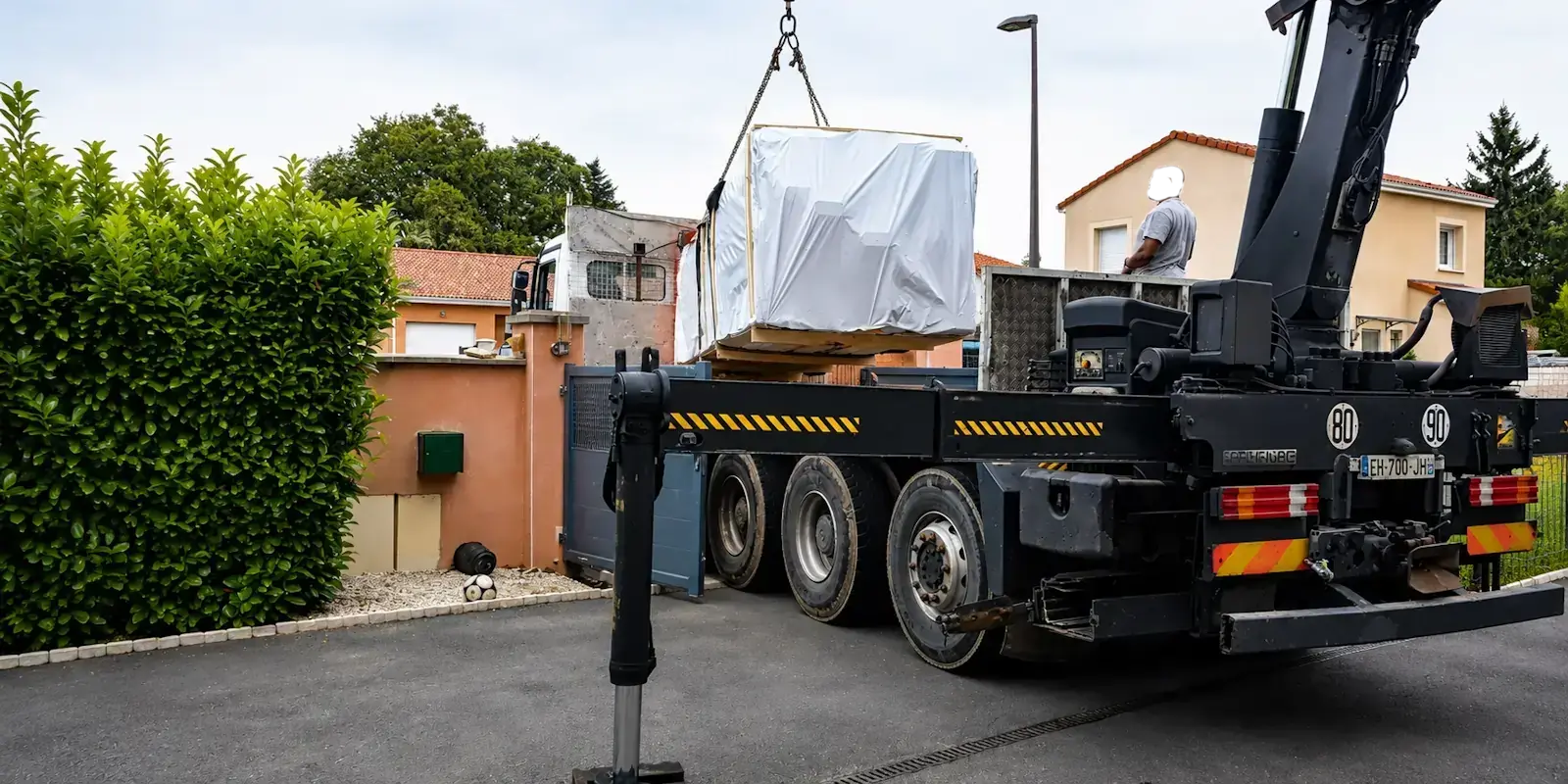 Déchargement d'un chalet en bois par camion-grue lors d'une livraison à domicile sur le terrain du client.